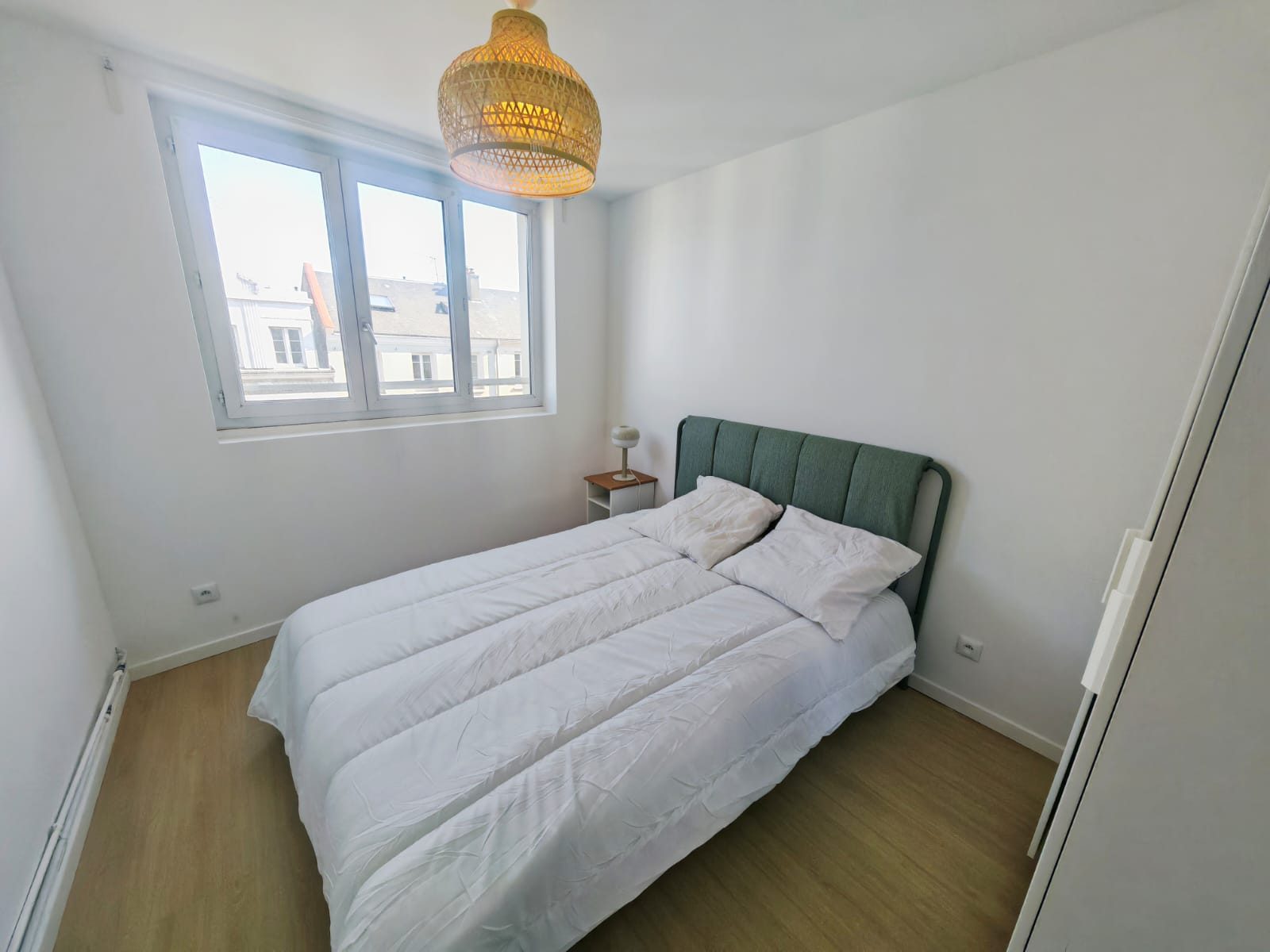 Chambre avec lit double, tête de lit capitonnée et vue sur les toits