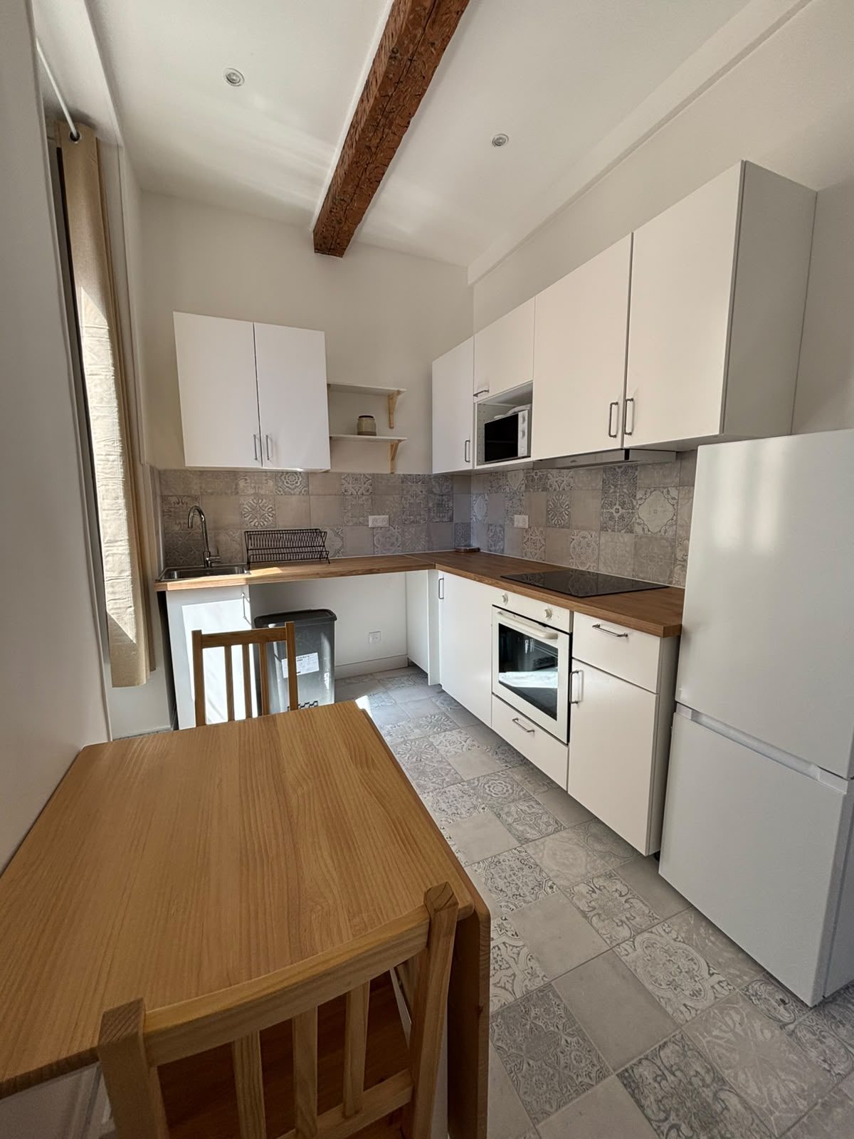 Cuisine équipée neuve du T2 à Marseille — crédence en carreaux anciens, four, plaques et coin repas en bois