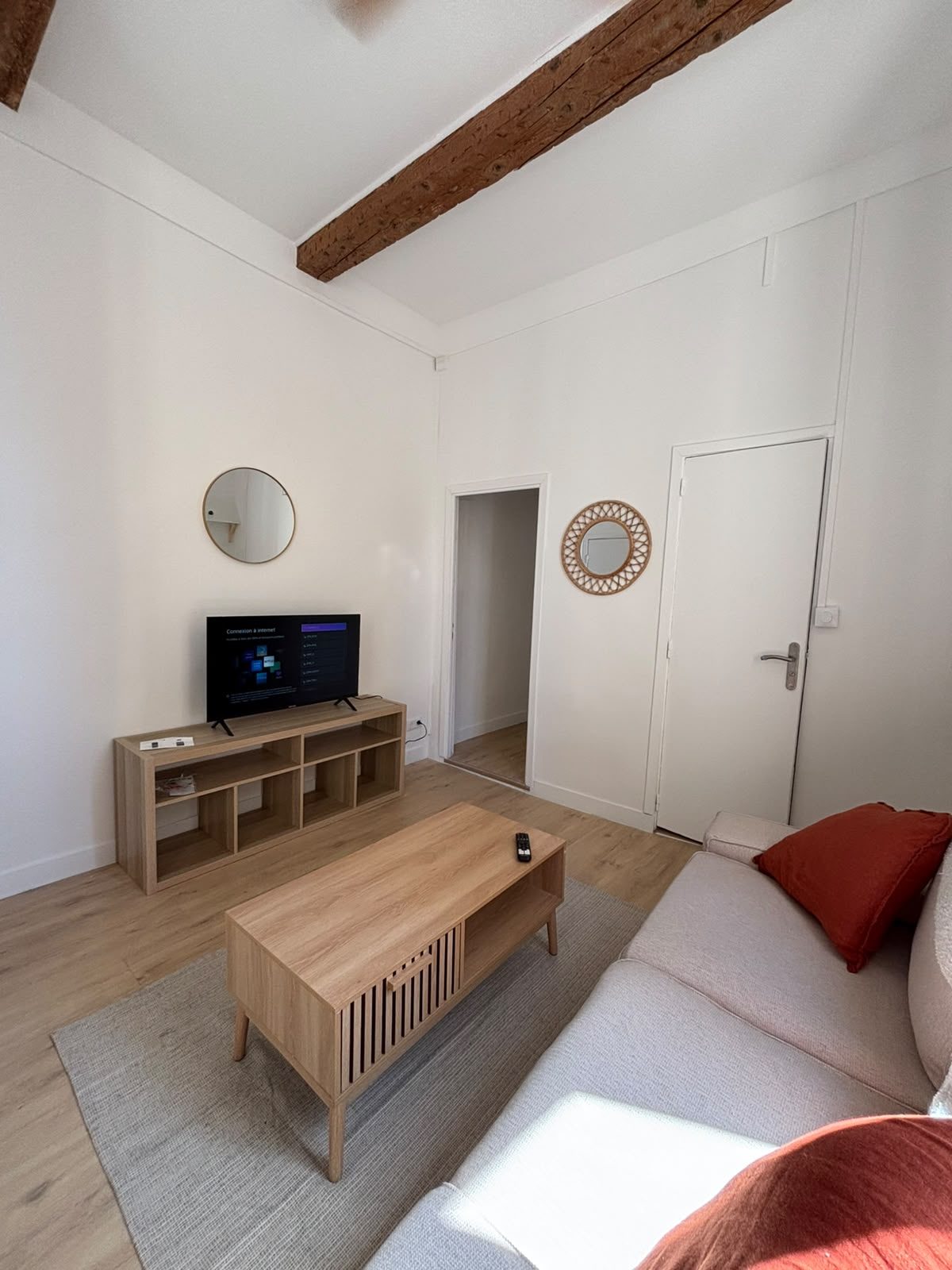 Coin télévision du T2 meublé clé en main à Marseille — meuble bas en bois et entrée de l
