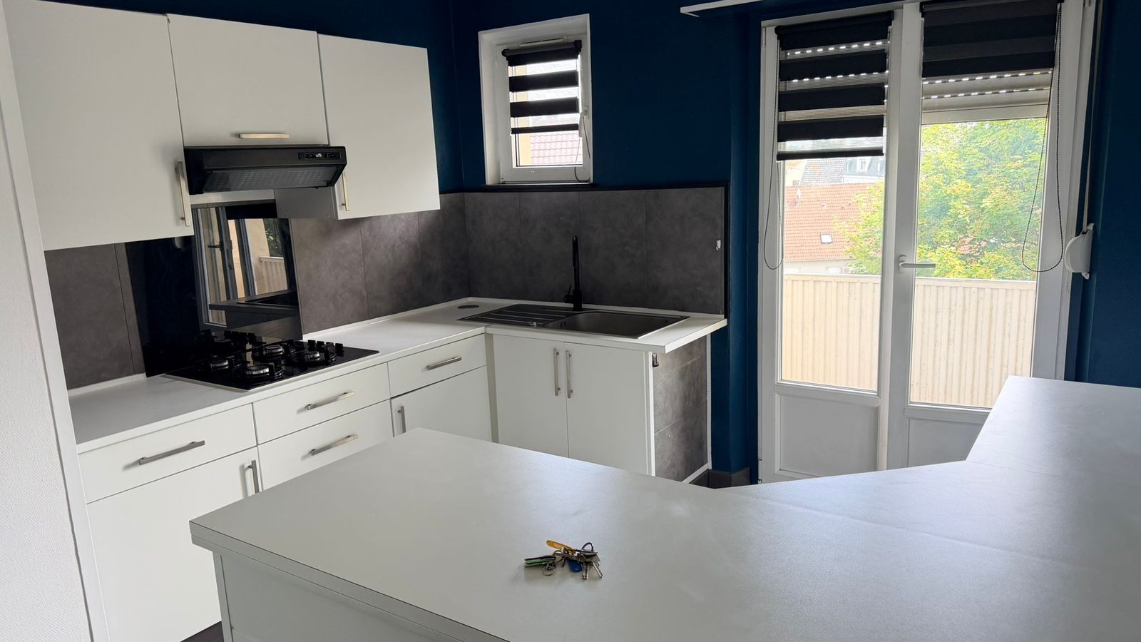 Cuisine équipée du 3 pièces à Mulhouse — façades blanches, plaque gaz et accès balcon