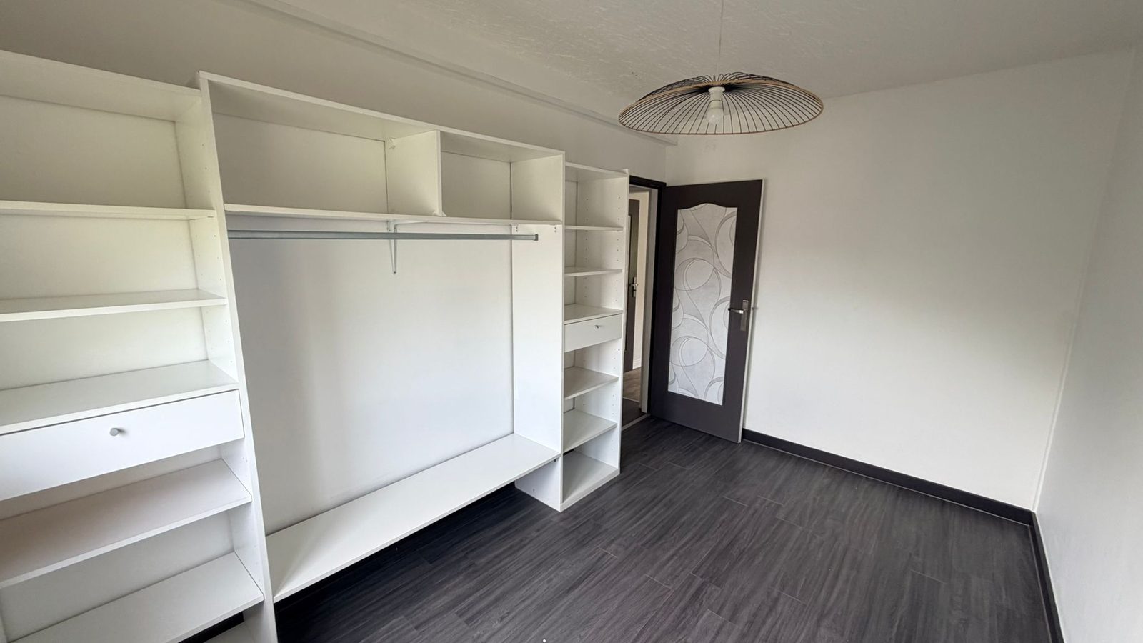 Espace dressing du 3 pièces — colonne d’étagères blanches et porte rénovée
