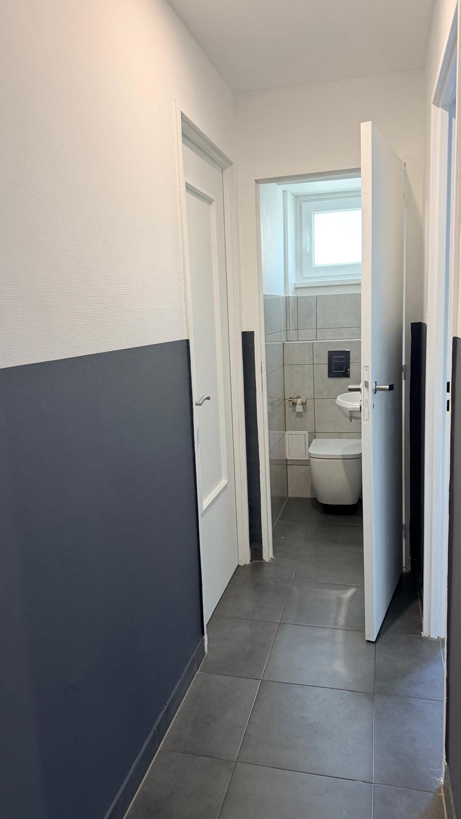 Couloir et WC séparé du T4 à Mulhouse Fridolin — soubassement bleu nuit et sol carrelé
