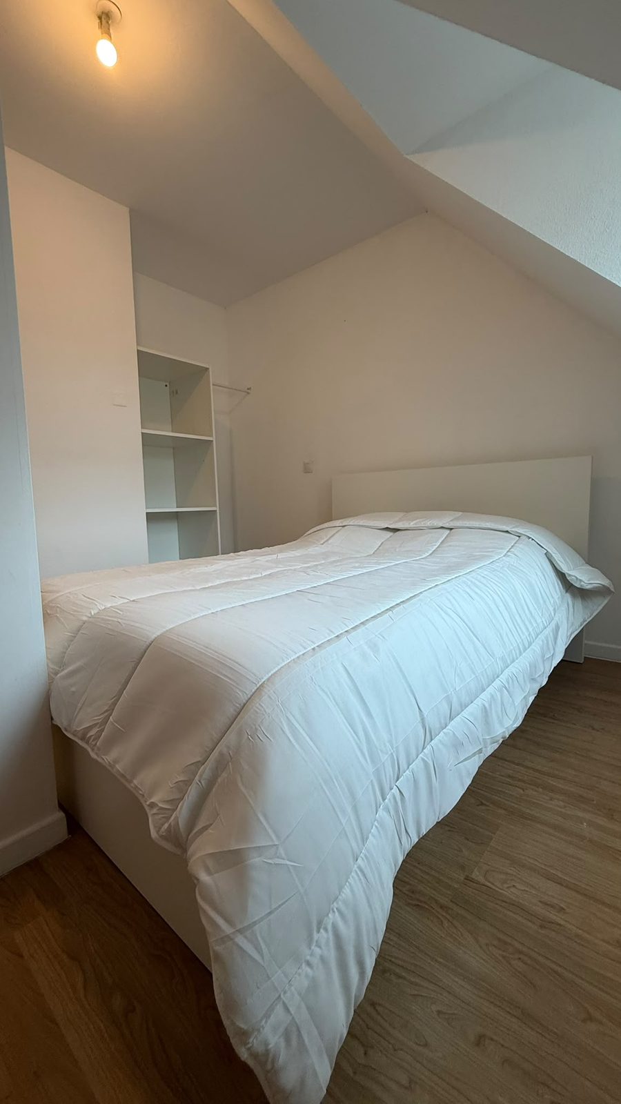 Deuxième chambre sous rampant avec lit double et étagère de rangement
