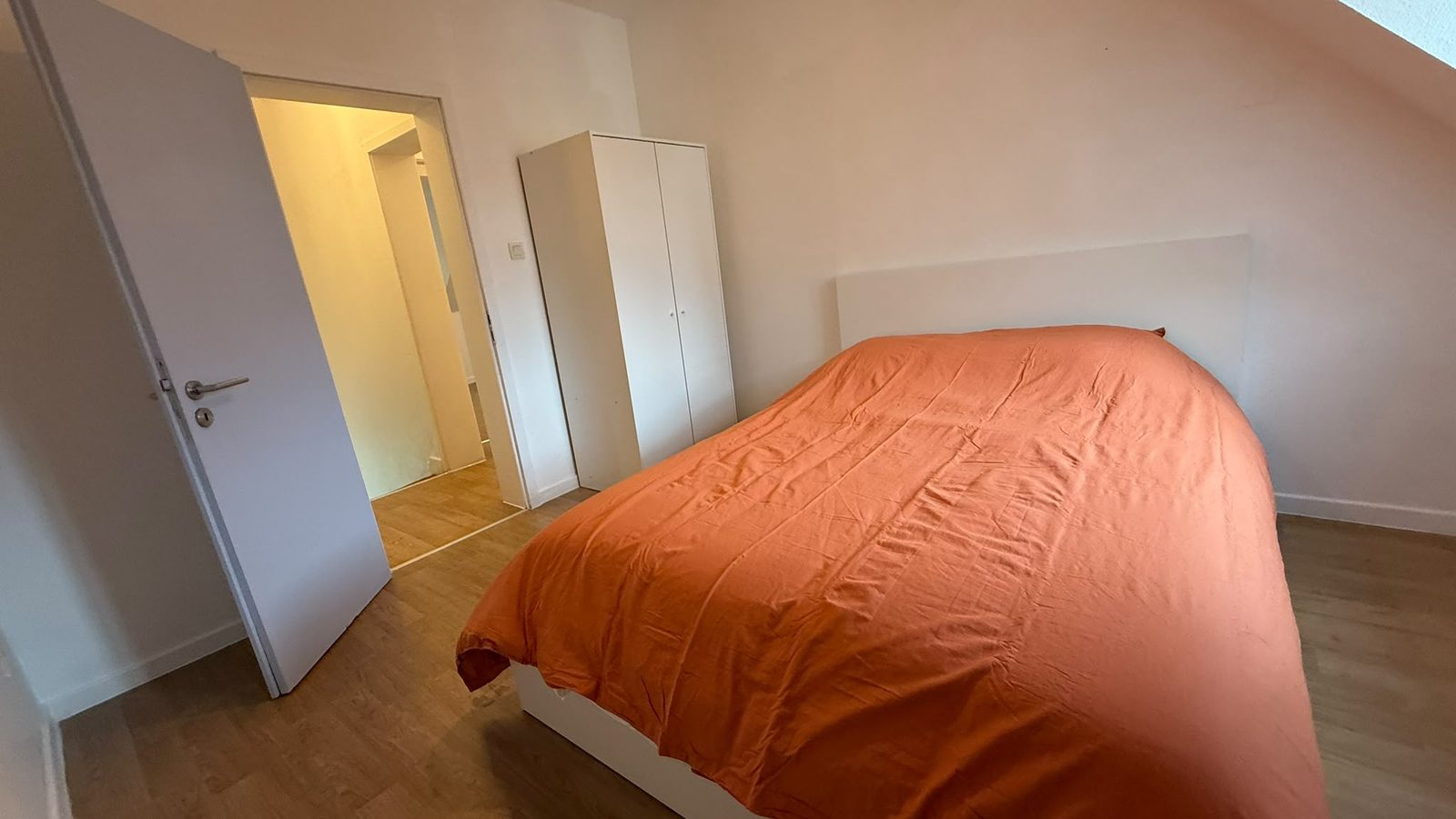 Chambre avec lit double et armoire blanche deux portes